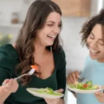 Dua orang wanita sedang makan makanan sehat untuk diet di akhir tahun
