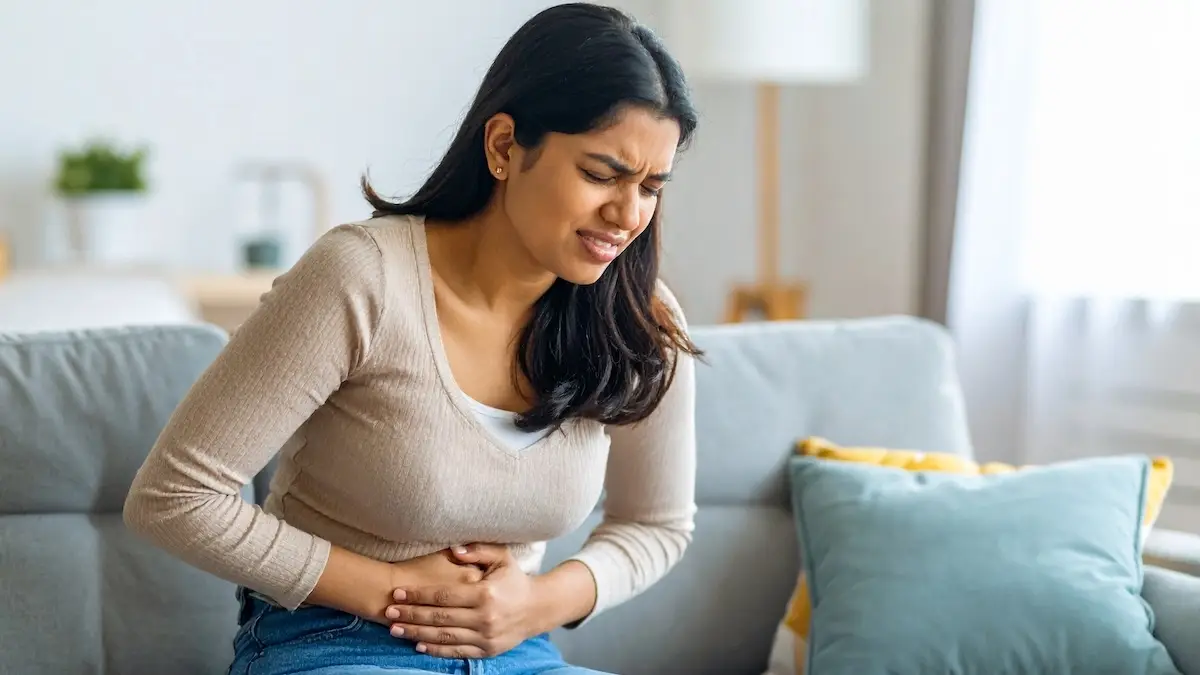 wanita sedang mengalami sakit perut karena usus tidak sehat & pengaruh hormon