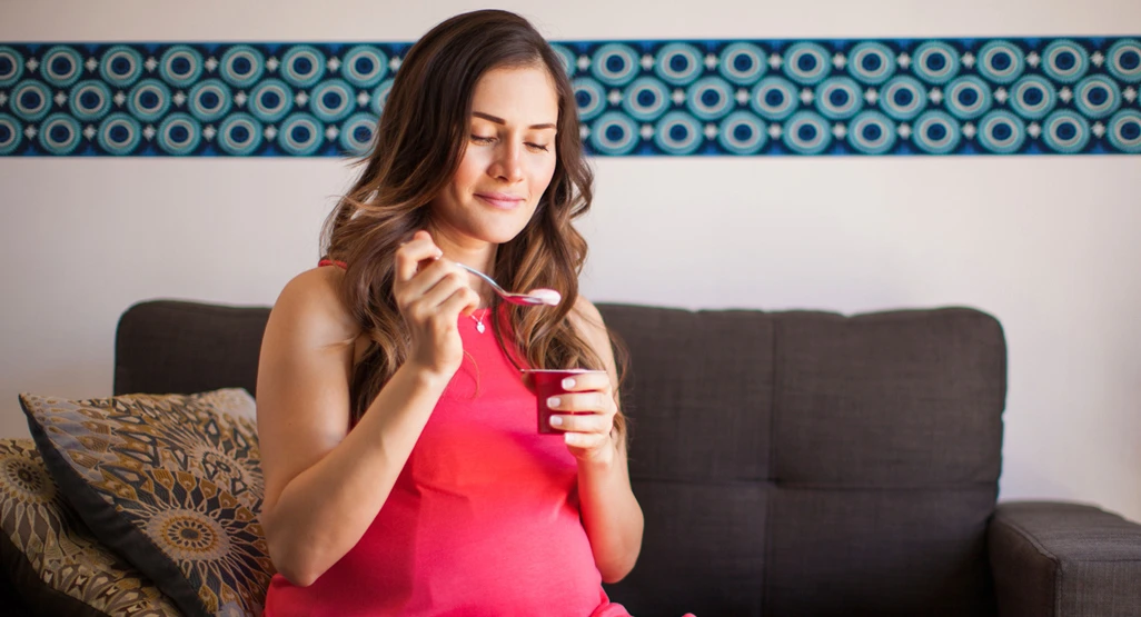 seorang perempuan hamil sedang mengonsumsi probiotik