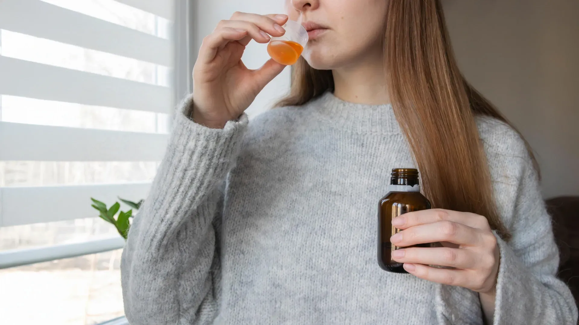 seorang wanita sedang minum probiotik cair