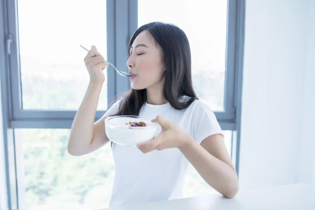 Wanita mengonsumsi probiotik seperti yogurt untuk membantu gut health dan mengurangi gejala PCOS